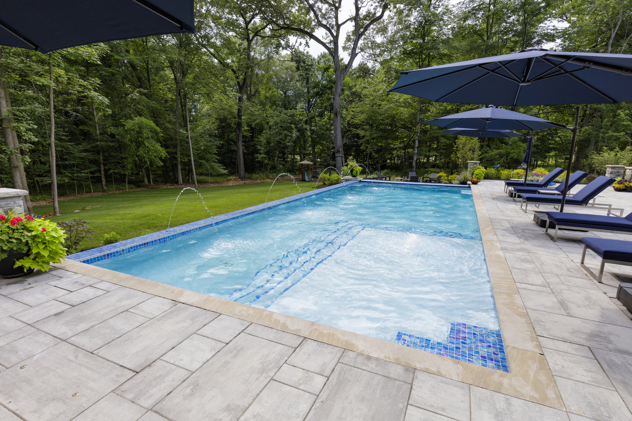 Rectangular pool installed with large white steps and fountains.